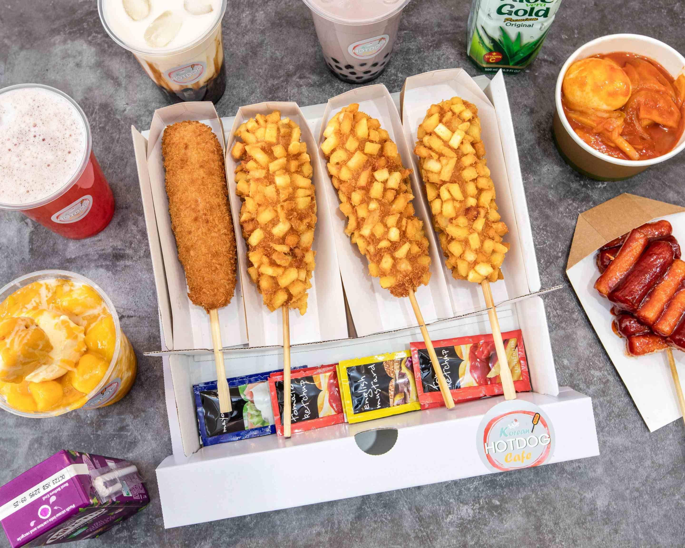 Grilled sausages on wooden skewers arranged on a street food cart tray, vendor's hand holding tongs nearby