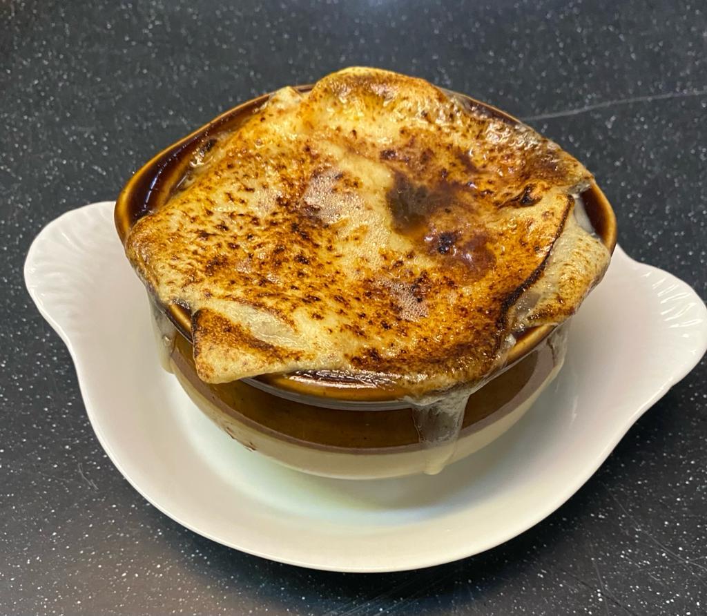 A bubbling crock of French onion soup with melted cheese crust at Le Petit Gourmet, Paris
