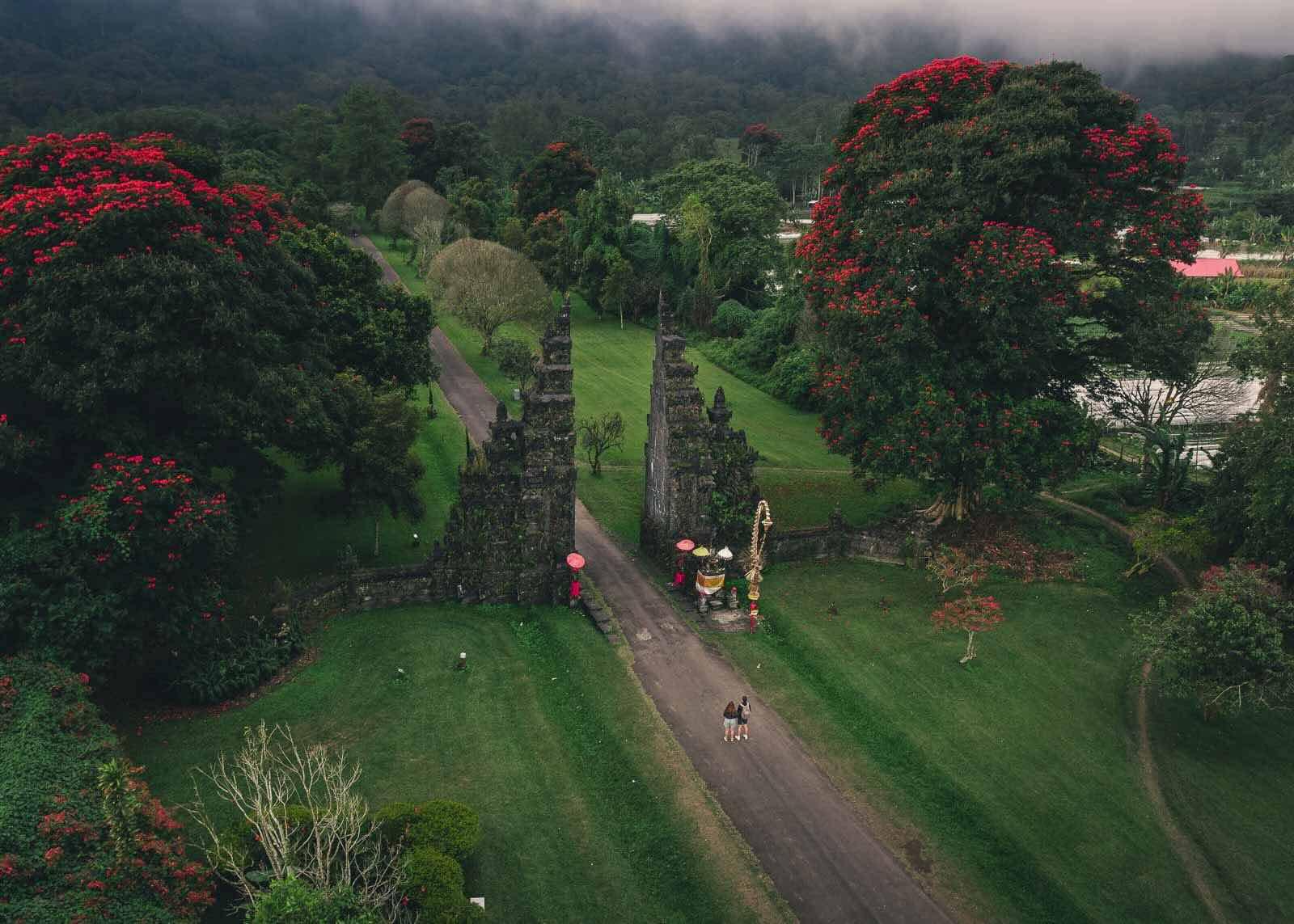 Moss-covered Handara Gate pillars with misty mountain road in North Bali