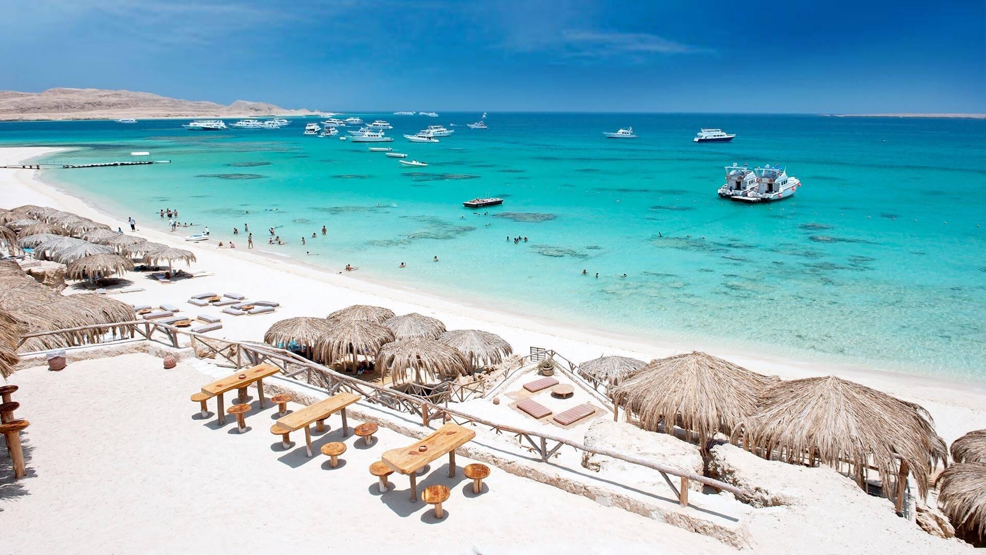 Turquoise Red Sea waters beside a rocky desert shoreline with arid mountains and radio towers in Hurghada, Egypt