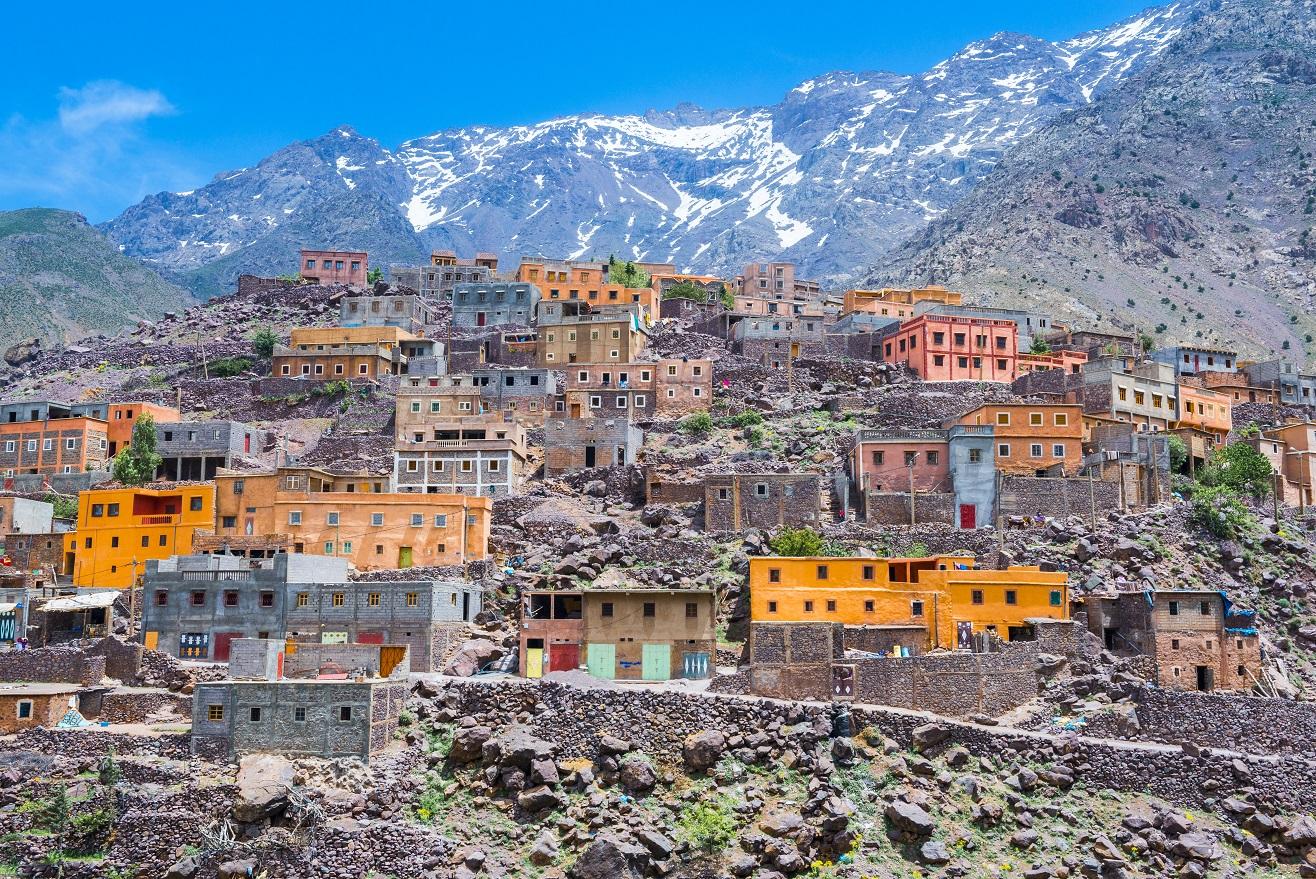 Koutoubia Mosque minaret rising above Marrakech rooftops with snow-capped Atlas Mountains in the background