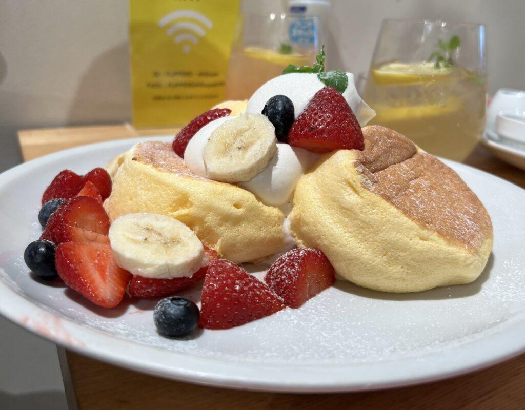 Stack of three jiggly Japanese soufflé pancakes at Flipper's Shibuya, topped with fresh strawberries and cream