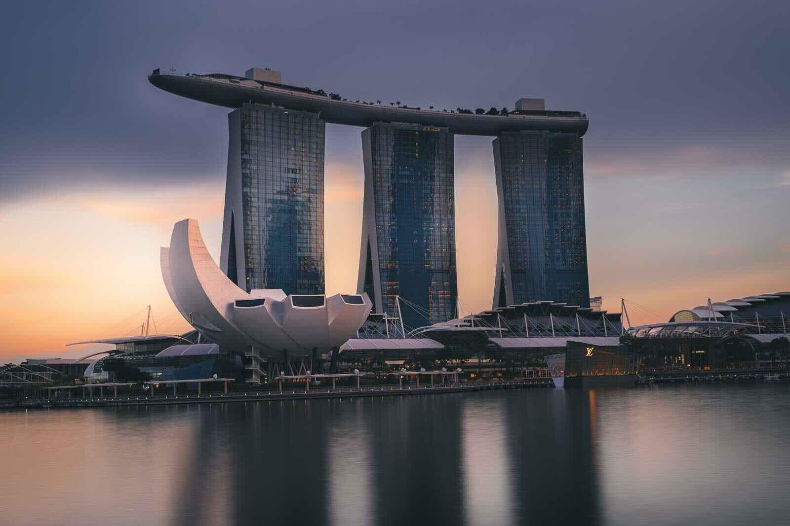 Singapore skyline at night with Marina Bay Sands, Gardens by the Bay domes, and Supertrees reflected on calm water