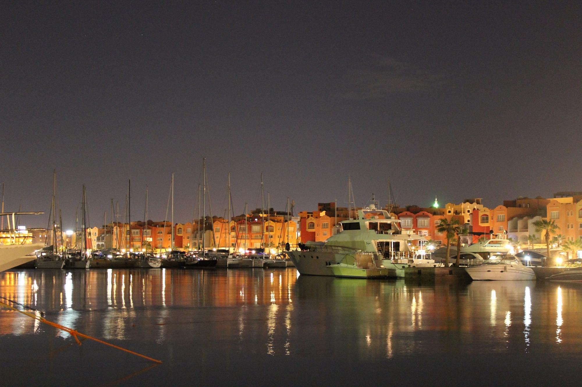 White King Fisher yacht docked at Hurghada Marina at sunset with orange sky and mountain silhouettes