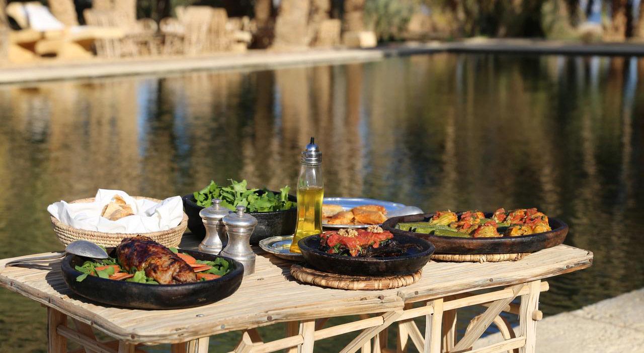 Traditional Siwan dishes including tagine and olives on a wooden table