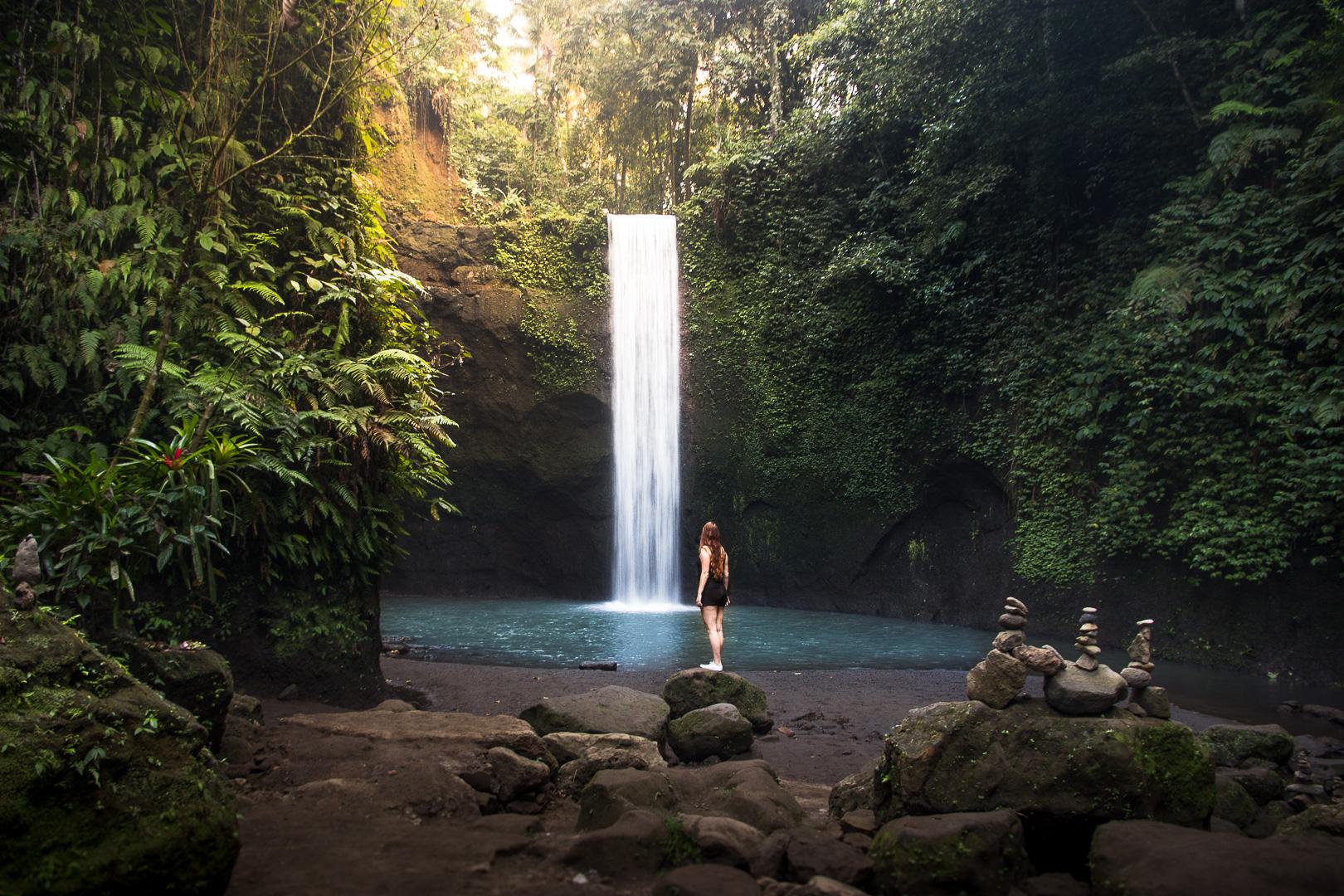 Twin tall waterfalls cascading down a lush moss-covered cliff surrounded by dense tropical jungle in Bali