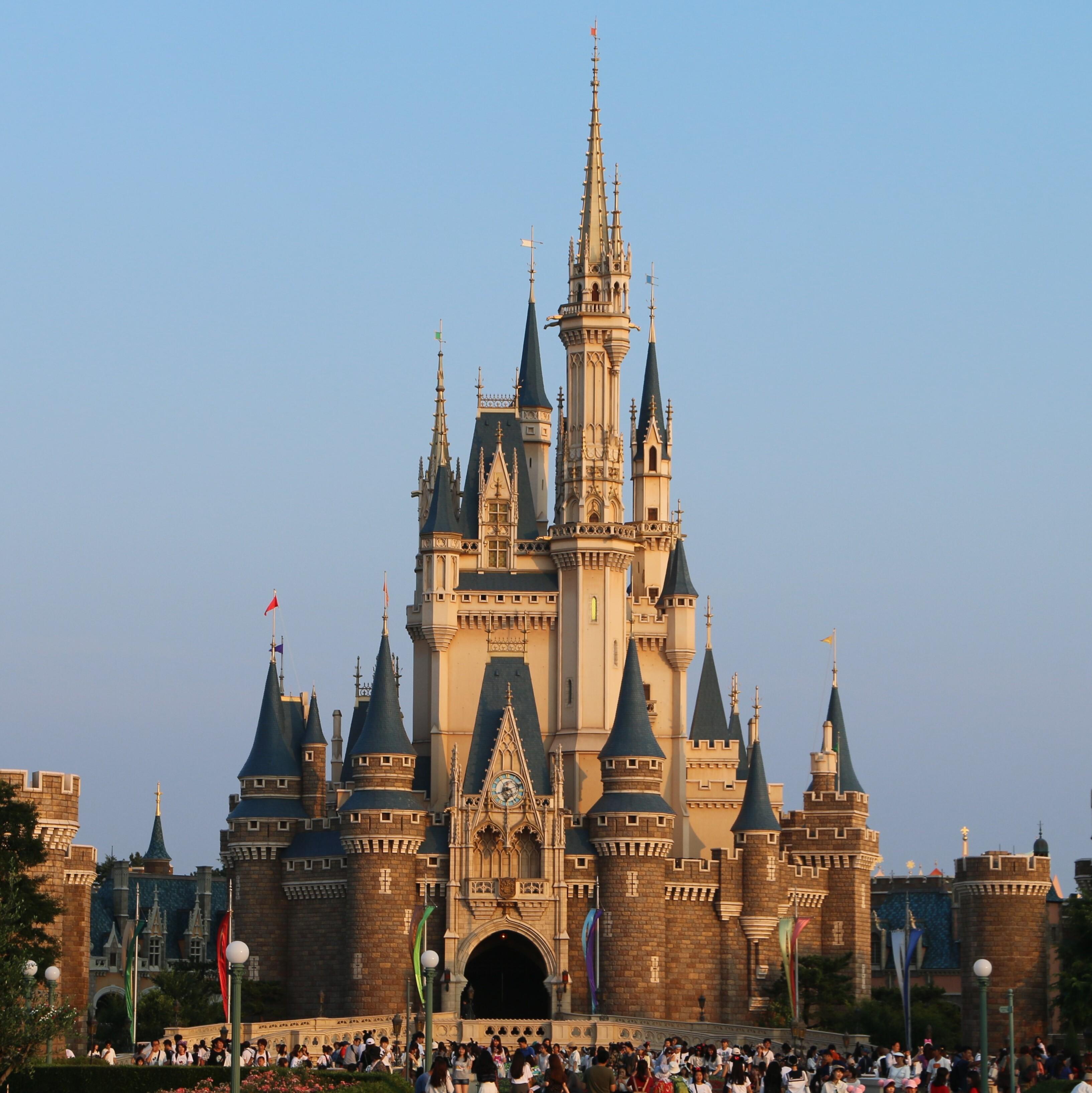 Tokyo DisneySea at dusk with illuminated Tower of Terror, red-funneled steamship, and harbor reflections