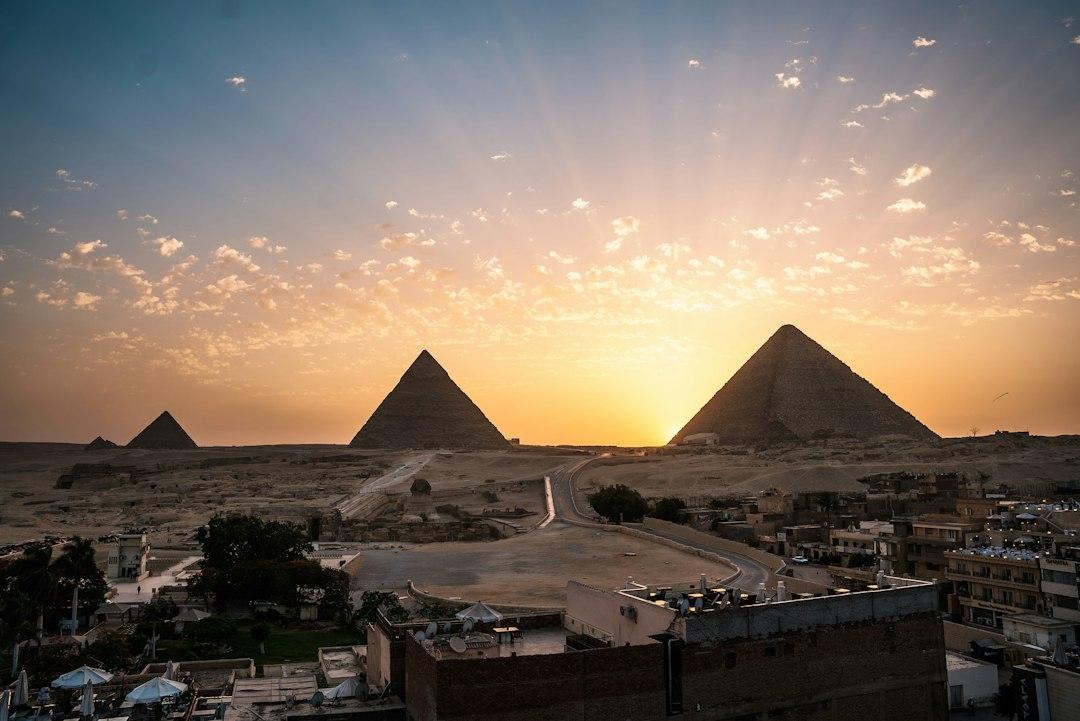 Panoramic sunset view over the three Giza Pyramids with the Sphinx and Cairo city buildings in the foreground