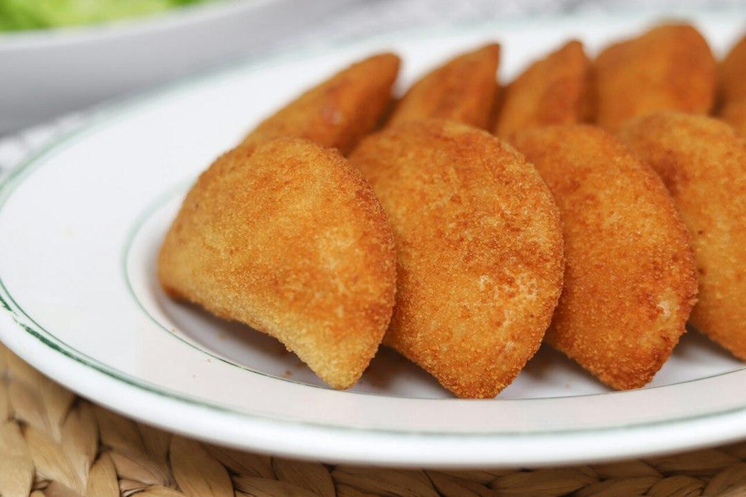 Golden fried kibbeh pieces arranged on a white plate with green trim, served at Tawlet restaurant in Beirut