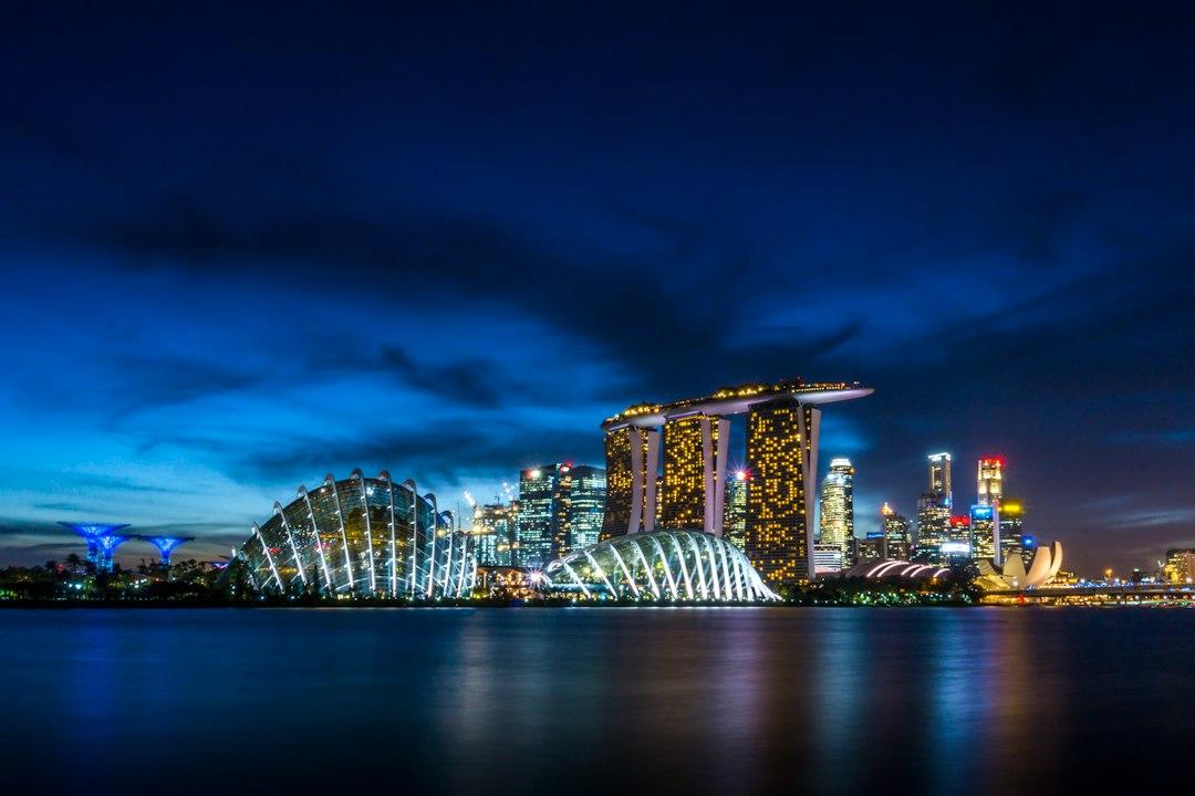 Singapore skyline at night with Marina Bay Sands, Gardens by the Bay domes, and city lights reflecting on calm water