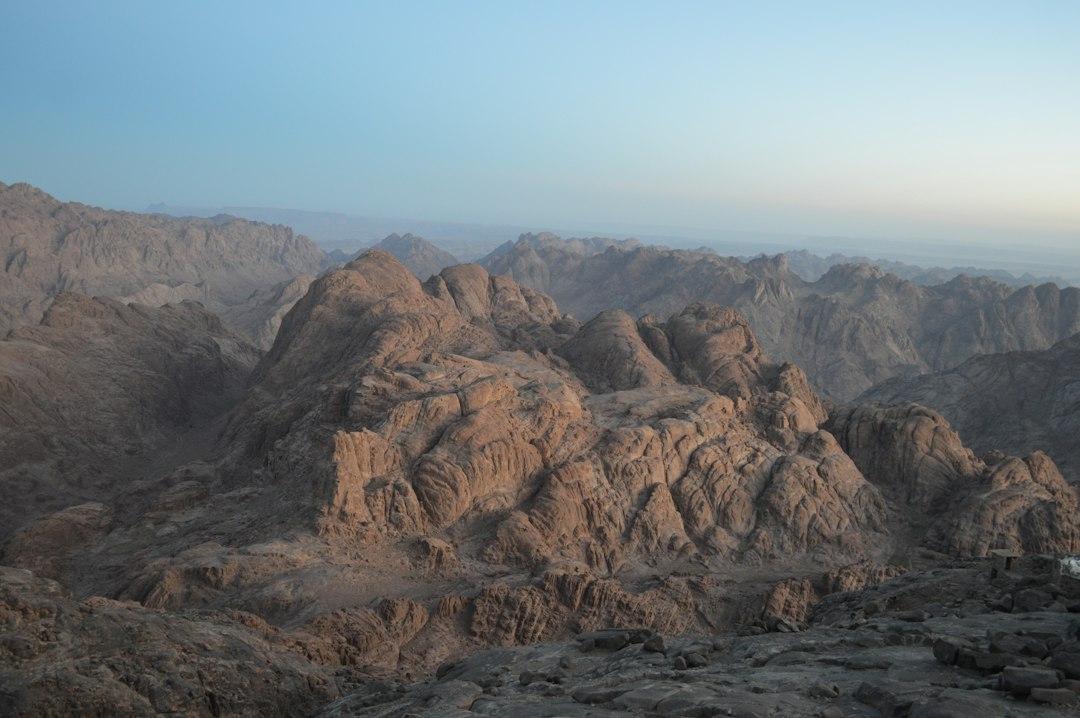 Rugged rocky peaks of South Sinai mountains stretching to the horizon under a pale blue dawn sky, Egypt