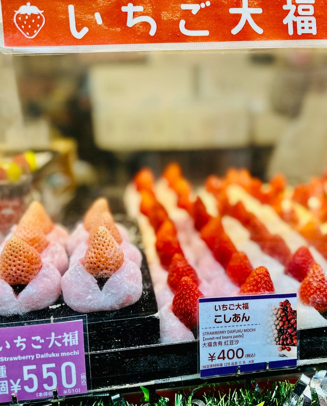 Strawberry daifuku mochi display in Japan, whole fresh strawberries wrapped in soft pink mochi, priced at ¥400–¥550