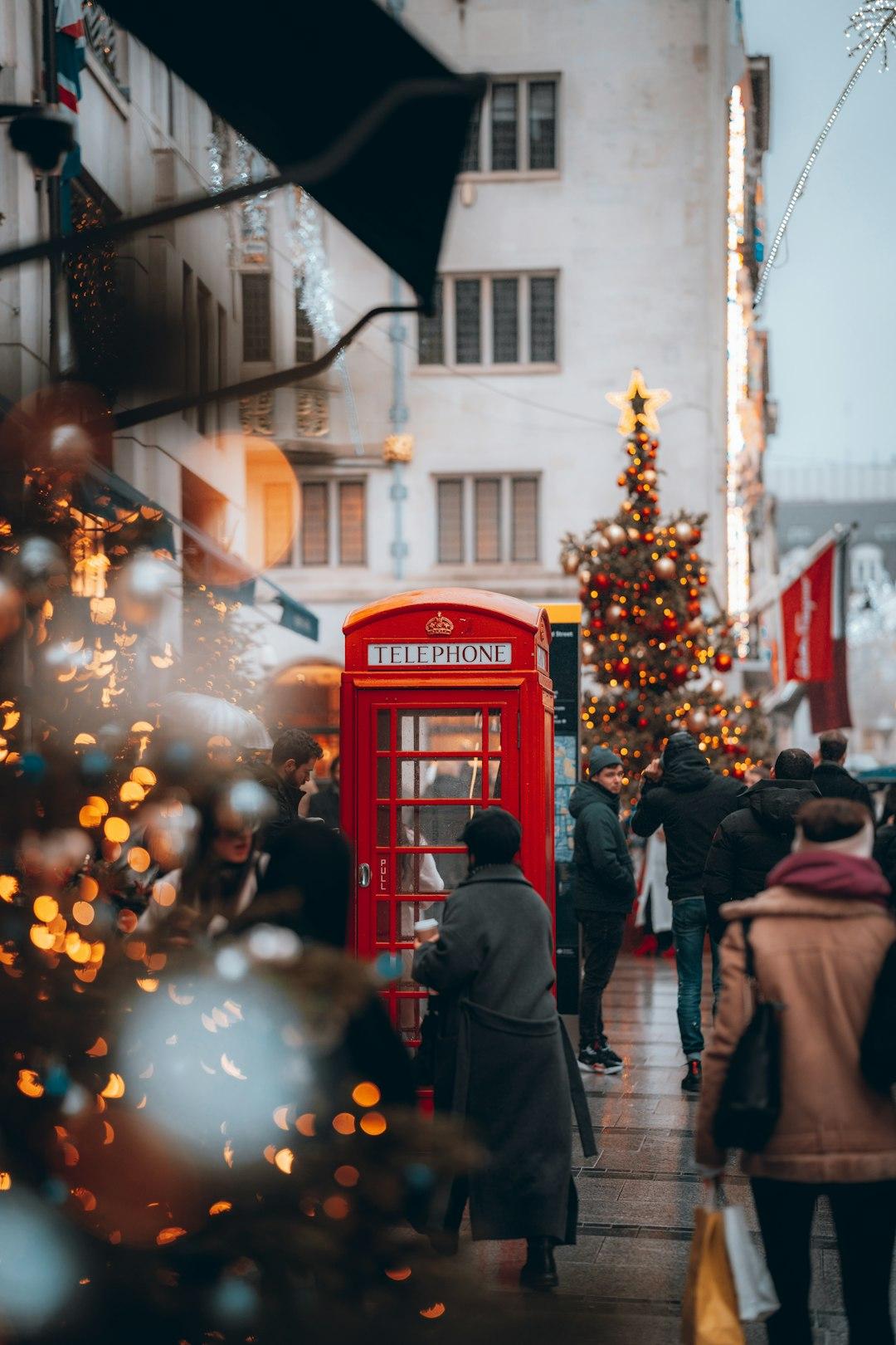 Busy London street at Christmas with a red telephone box, decorated tree, and festive lights near Borough Market