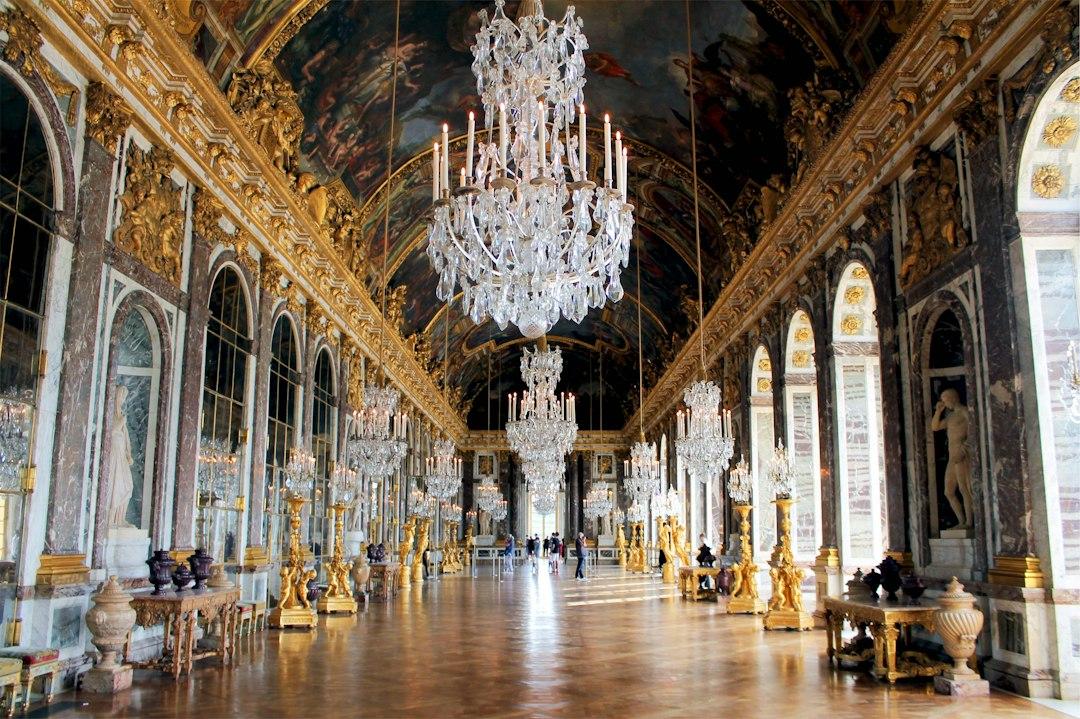 Hall of Mirrors at Versailles with crystal chandeliers, gilded decor, painted ceilings, and parquet floors