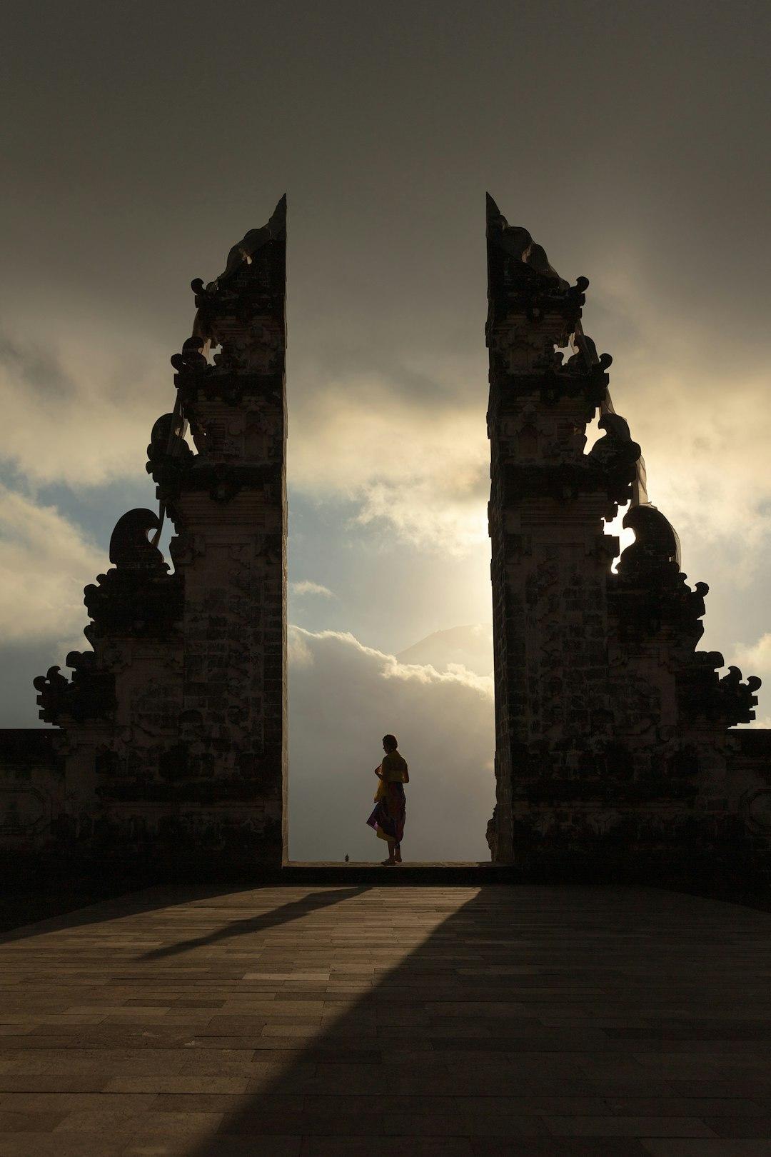 Silhouette of a person standing in the split gate of Lempuyang Temple, Bali, framed by dramatic cloudy sky