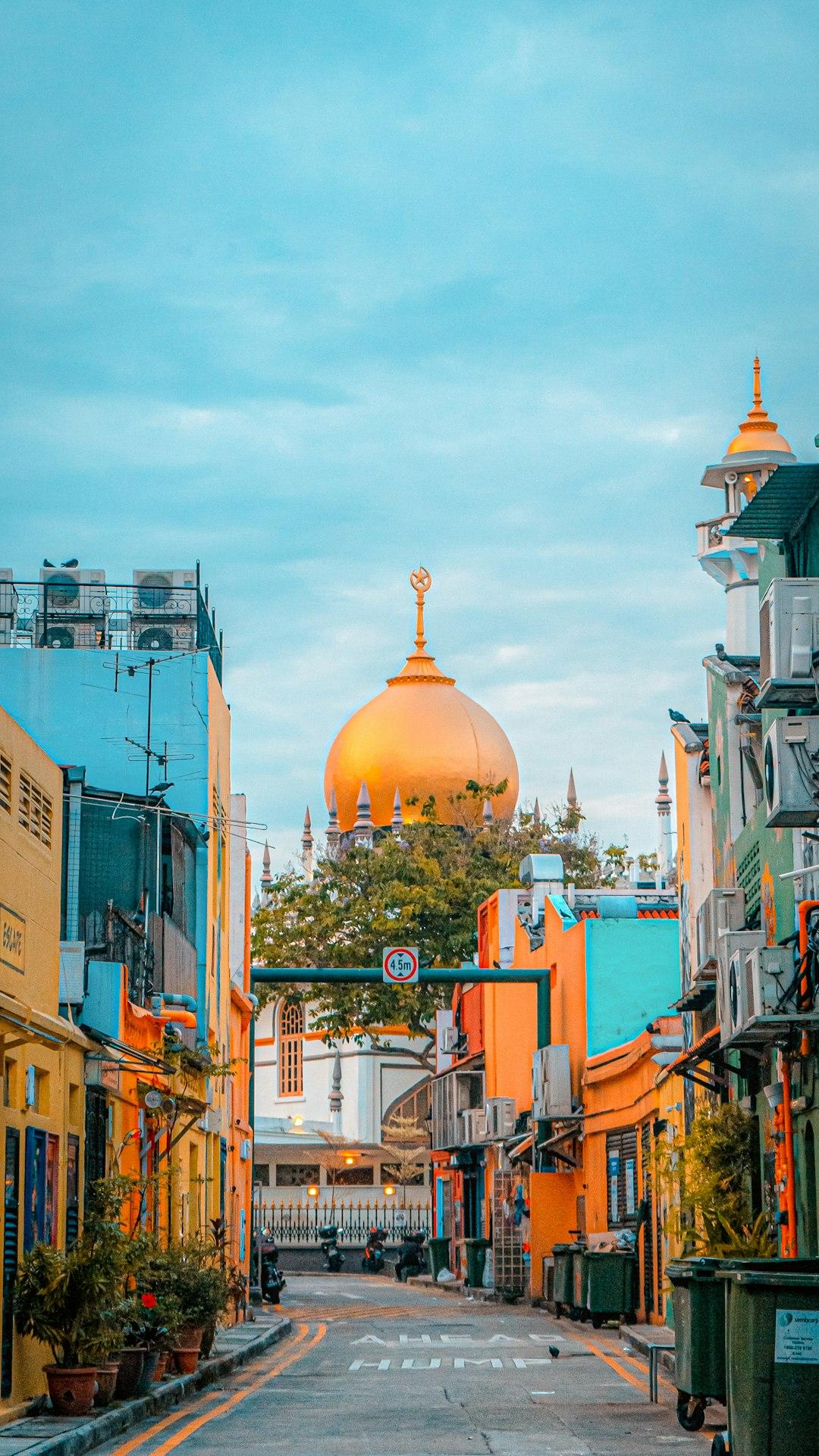 Colorful shophouses lining a narrow street in Kampong Glam with Sultan Mosque's golden dome rising behind