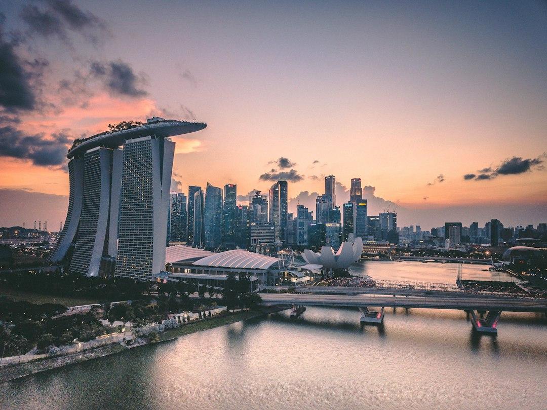 Aerial sunset view of Marina Bay Sands hotel and Singapore skyline reflected in calm harbor waters