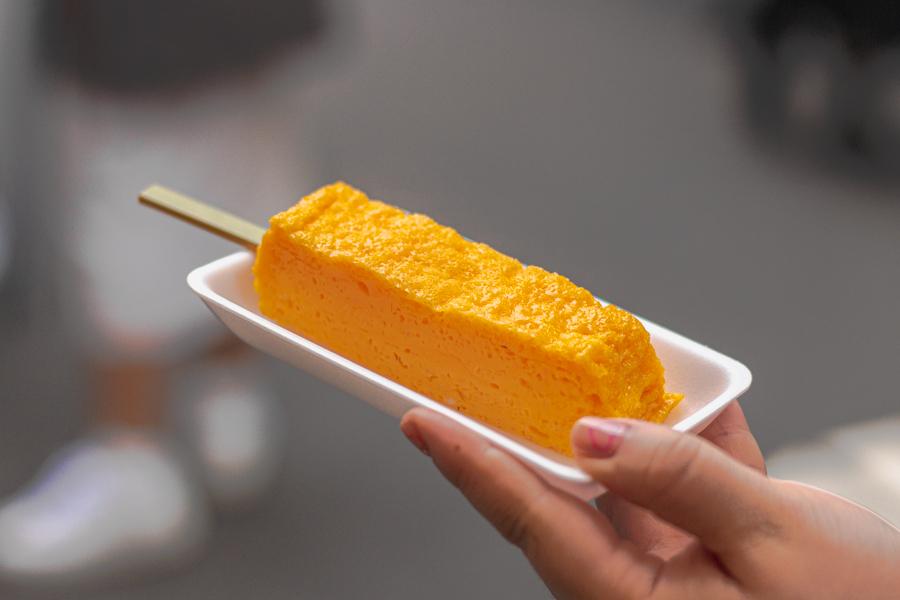 Warm tamagoyaki rolled omelette on a wooden skewer at Tsukiji Outer Market Tokyo
