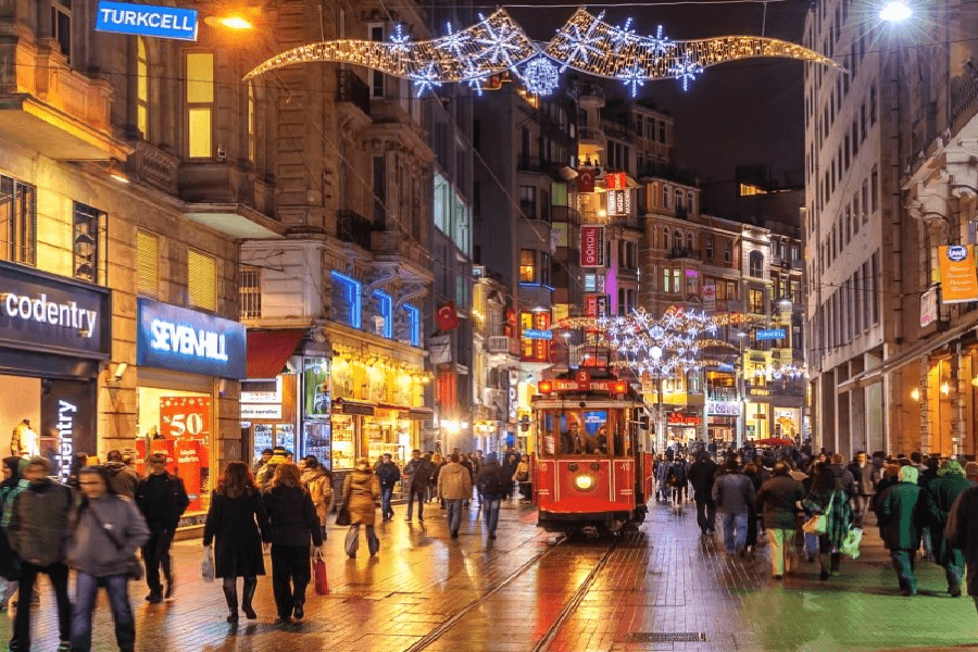 Red vintage tram on İstiklal Street with pedestrians and ornate buildings, Istanbul