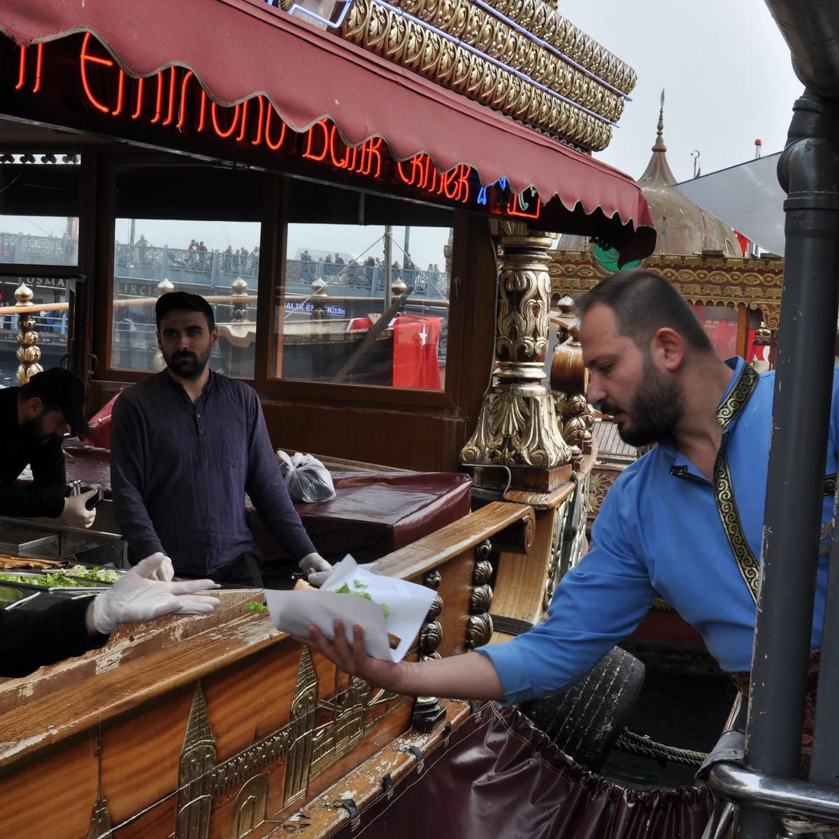 Fishermen casting rods off Galata Bridge in Istanbul, with the city's historic hillside skyline behind
