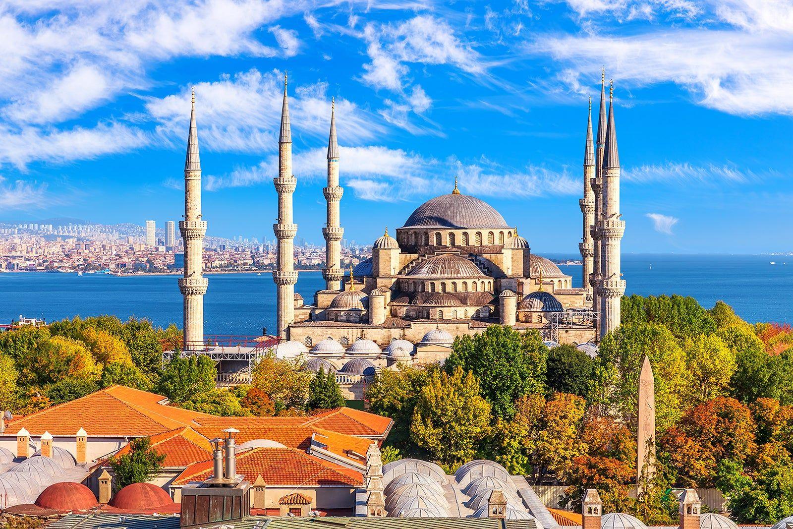 Blue Mosque's cascading domes and twin minarets silhouetted against a vivid pink and purple Istanbul sunset sky