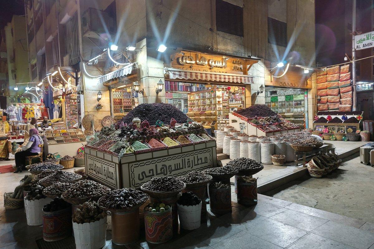 Colorful spice and craft stalls lining the shaded Aswan souk market street