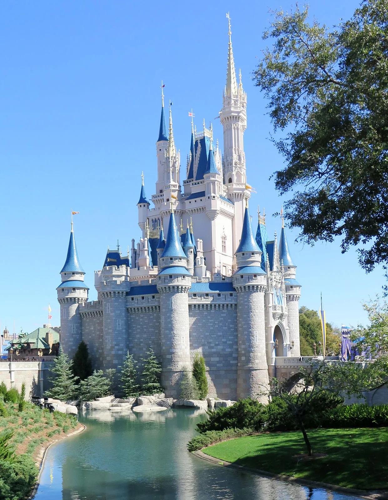 Cinderella Castle at Magic Kingdom, Walt Disney World, with teal spires and golden tips under a cloudy blue sky