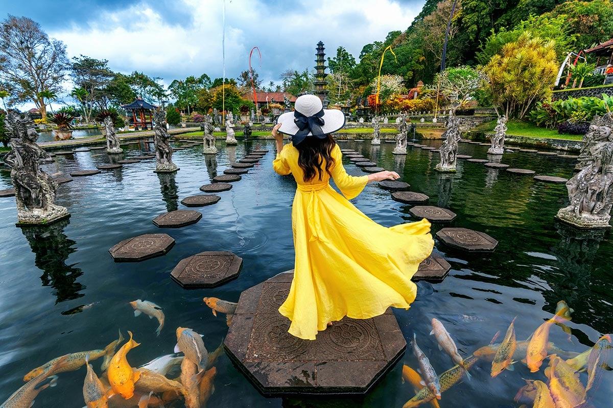 Visitors bathing at Tirta Empul temple's sacred spring pools surrounded by ancient Balinese stone carvings and water spouts