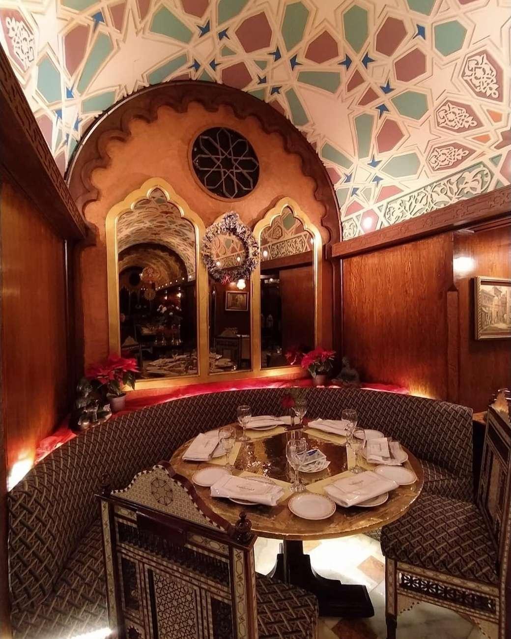 Colorful lanterns and brass goods fill a Khan El Khalili shop beside a stone archway in Islamic Cairo