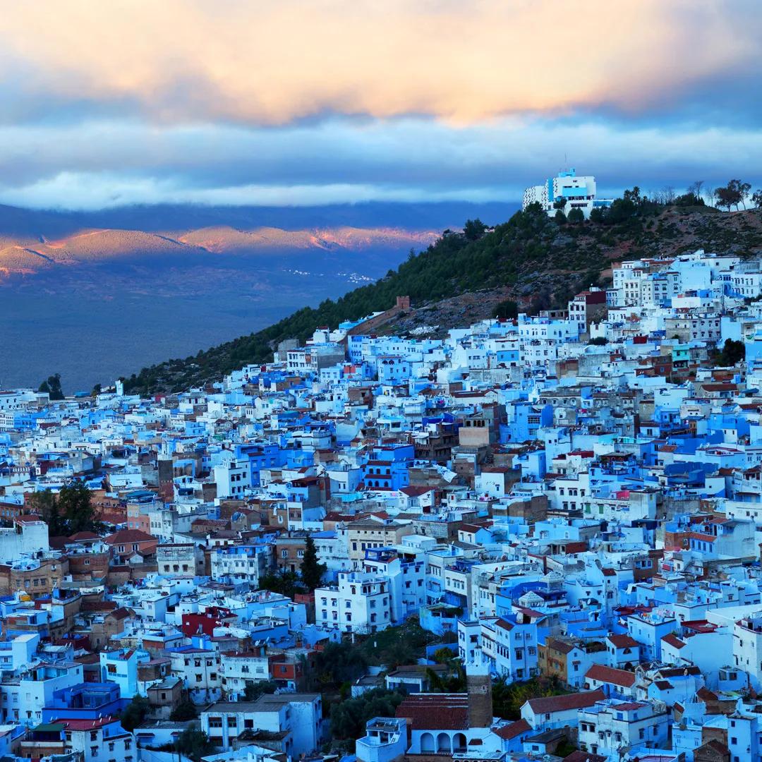 Blue-painted shop doorway lined with wooden shelves of goods in Chefchaouen medina, Morocco