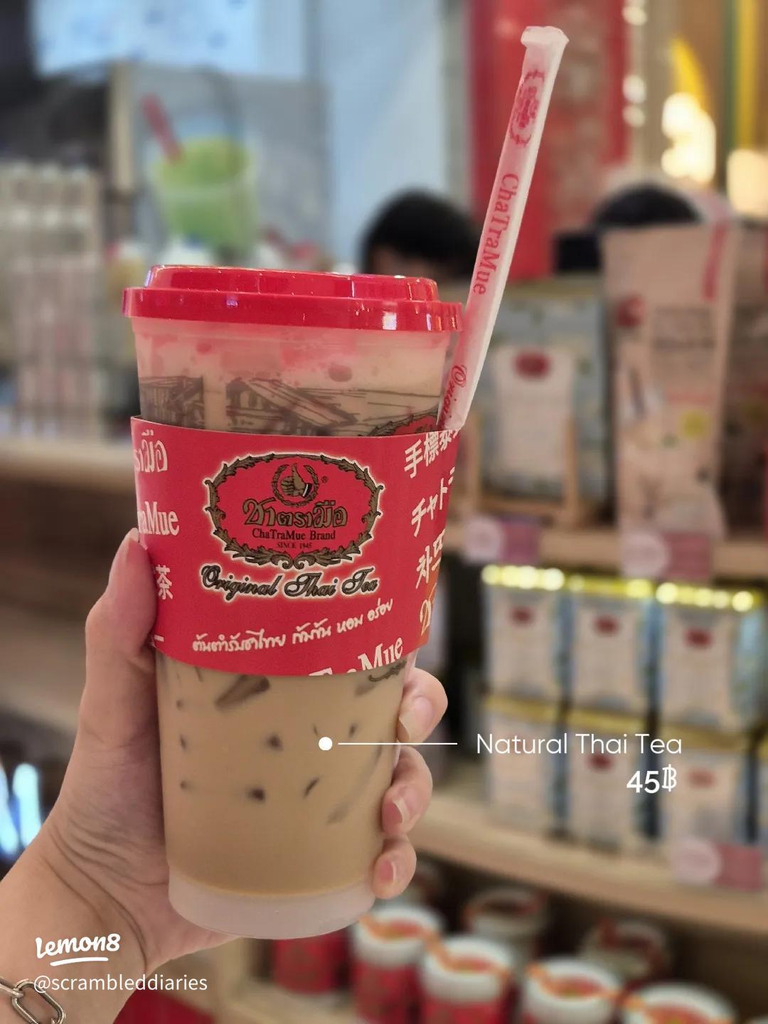 A tall glass of Thai iced milk tea with condensed milk swirling at Auntie Nid's stall in Bangkok's Phra Nakhon district