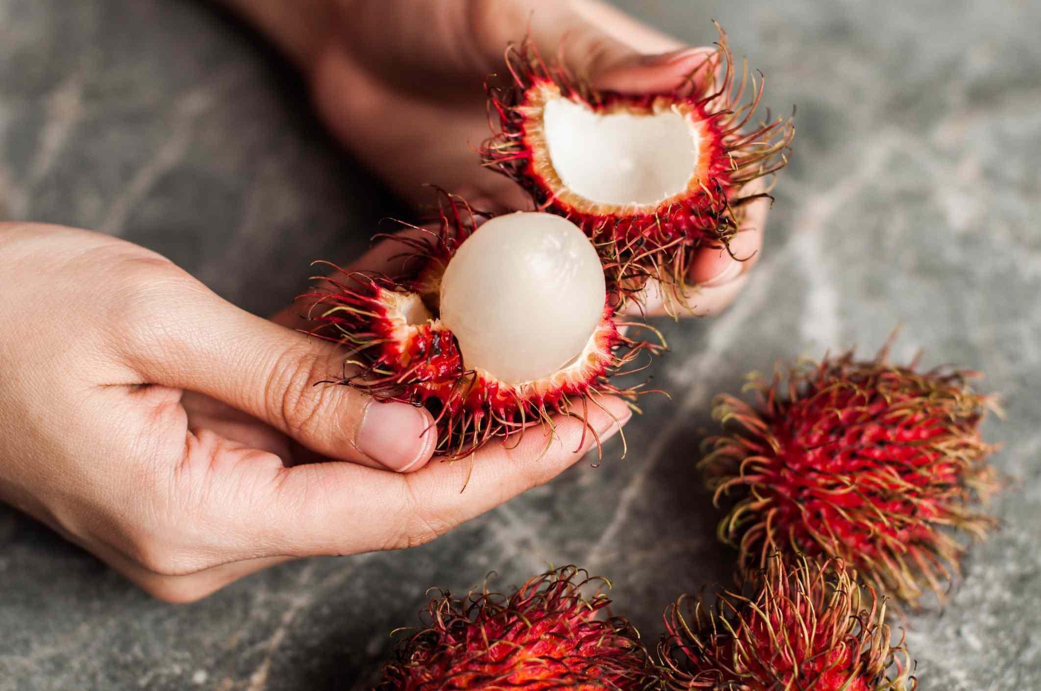 Red spiny rambutan fruits piled high on a night market stall in Seminyak Bali