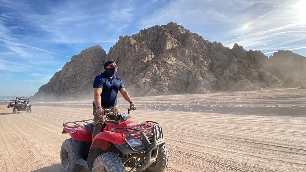 Solo rider on a quad bike crossing Egyptian desert dunes at sunset near Sahl Hasheesh