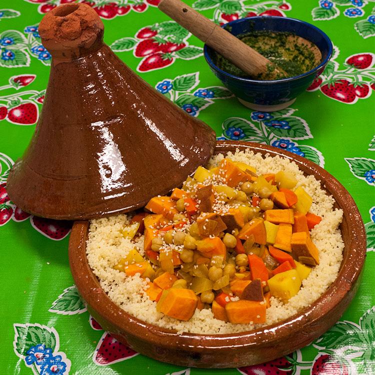 Pile of glazed terracotta Moroccan tagine lids with conical tops and engraved rings at a market