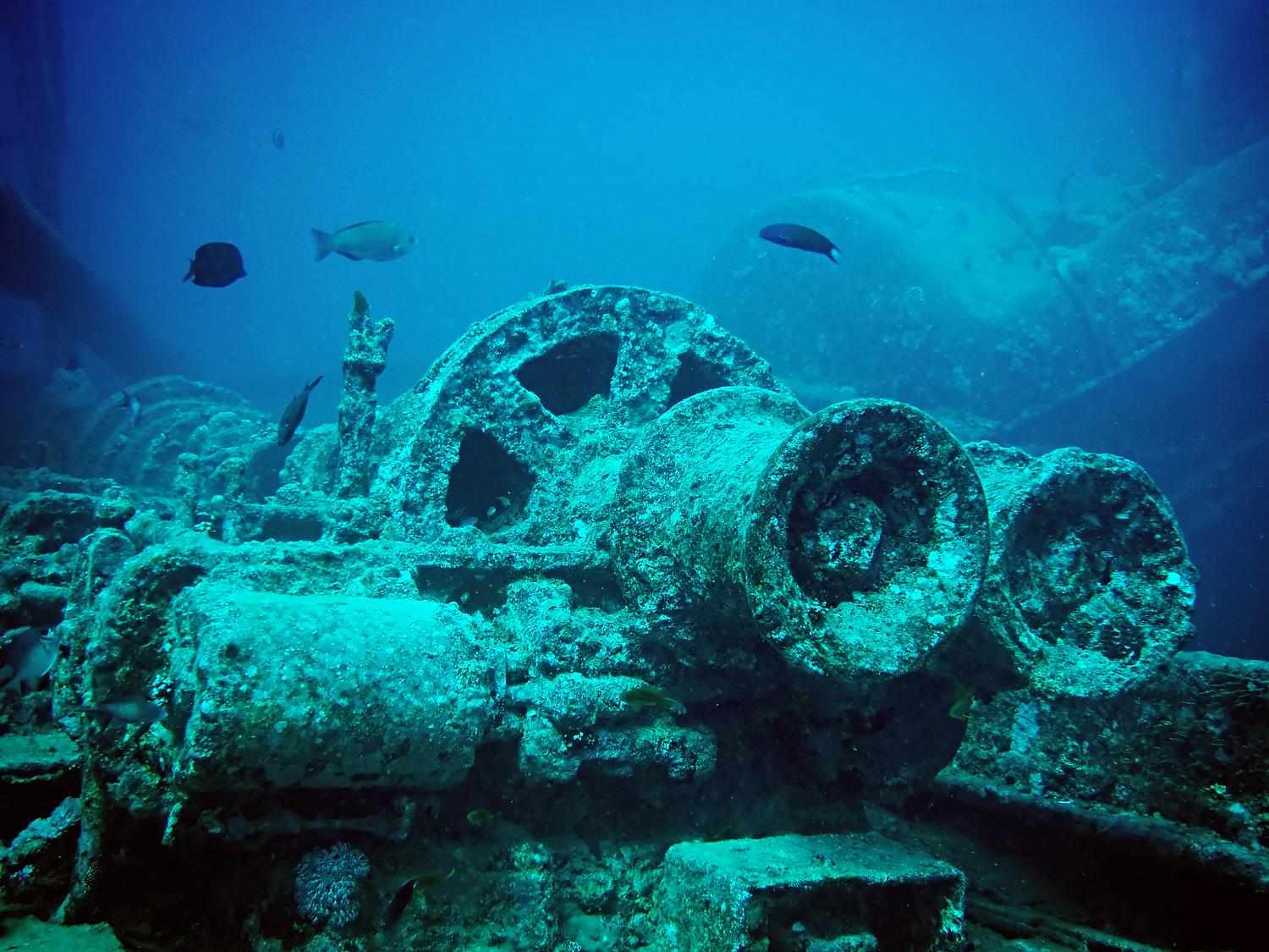 Rusty deck of a sunken shipwreck surrounded by vivid turquoise ocean under a bright blue sky