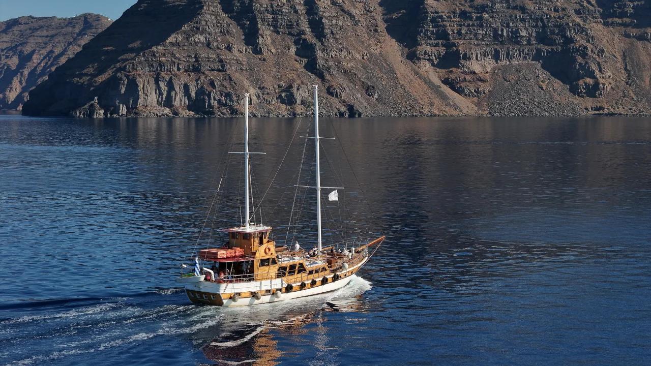 Panoramic view of Santorini's deep-blue caldera, volcanic cliffs, and volcanic islands from a whitewashed clifftop terrace