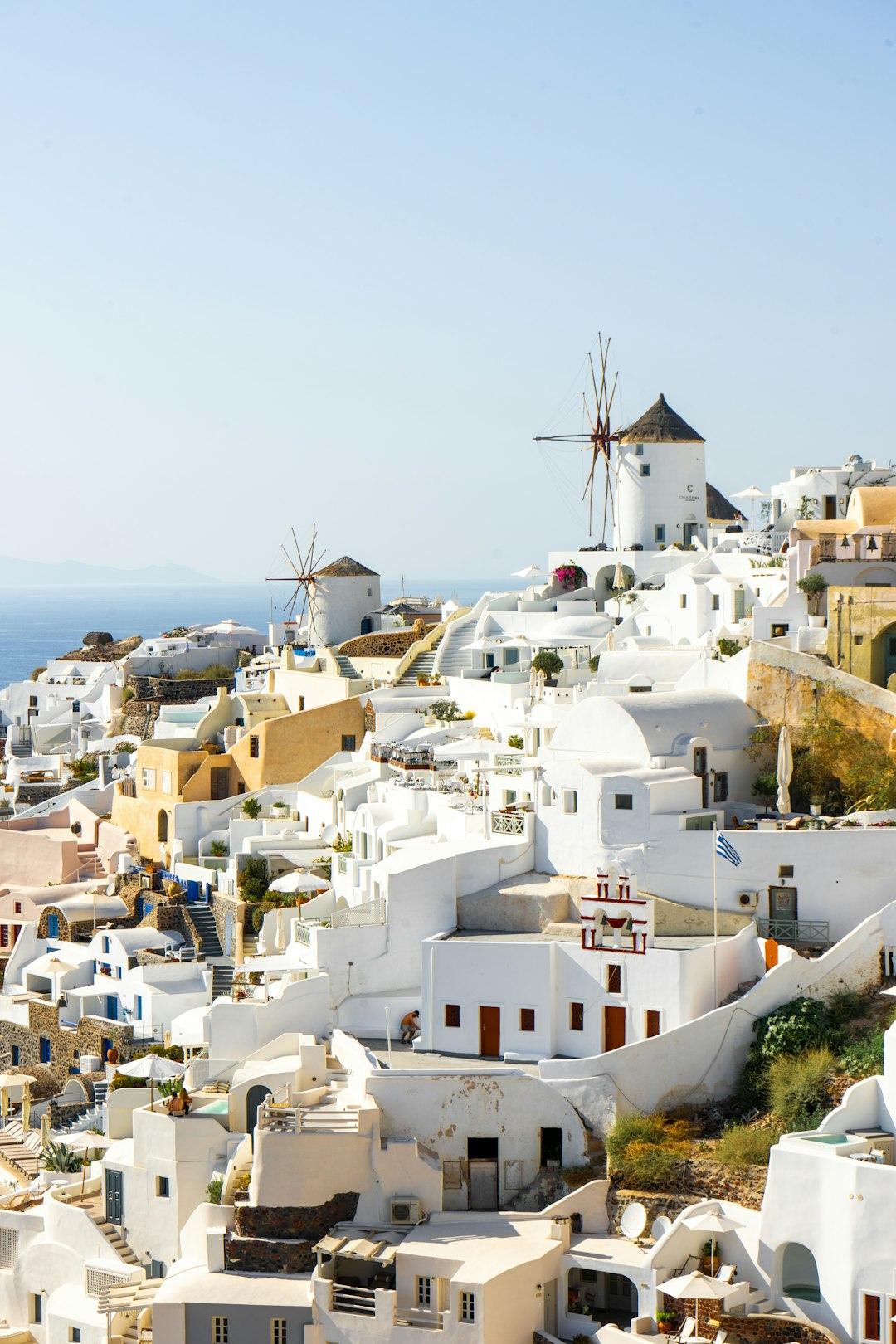 White-washed buildings and traditional windmills of Oia village cascade down Santorini's cliffside above the Aegean Sea
