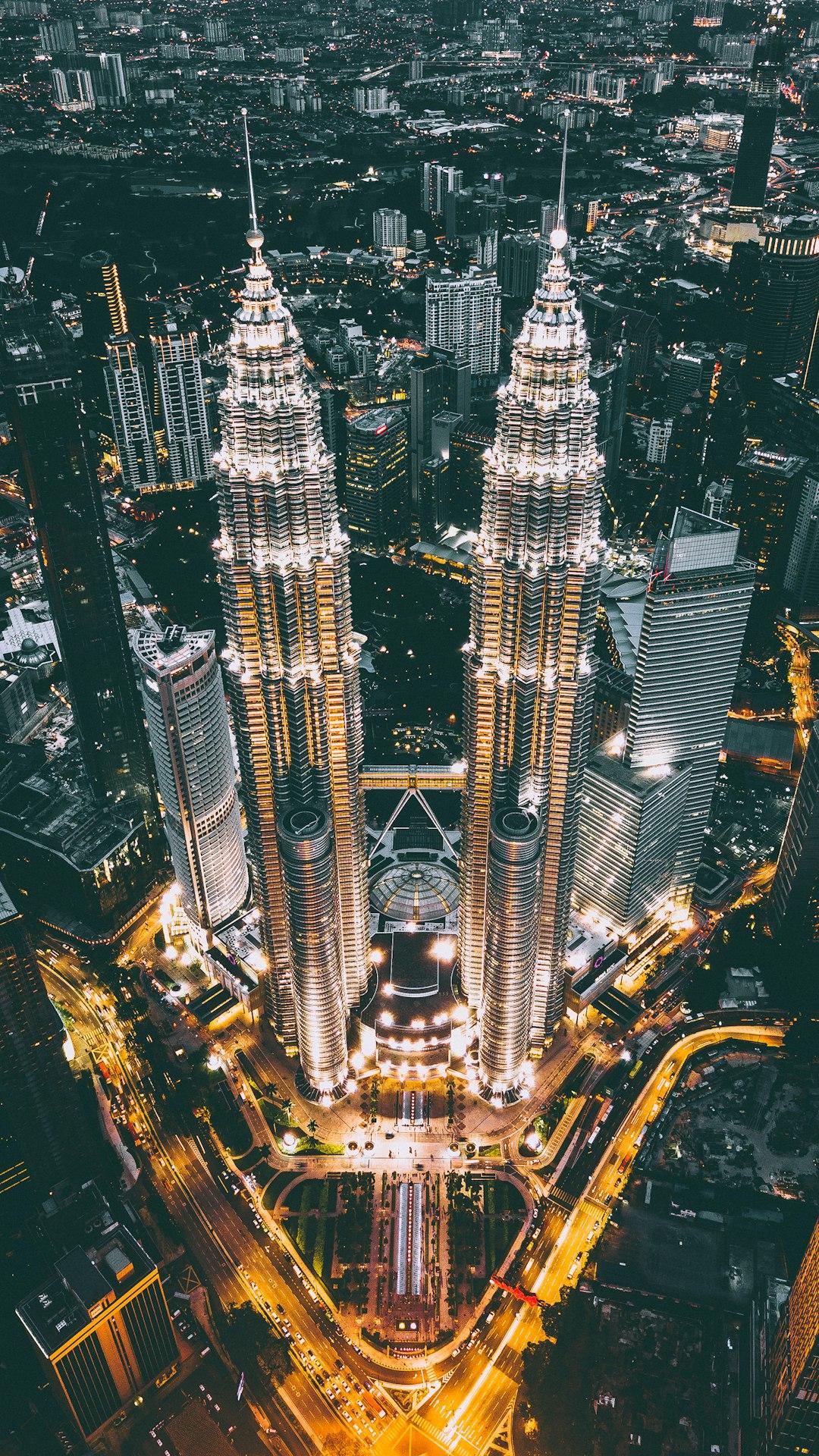 Aerial night view of Petronas Twin Towers glowing over Kuala Lumpur's illuminated cityscape, Malaysia