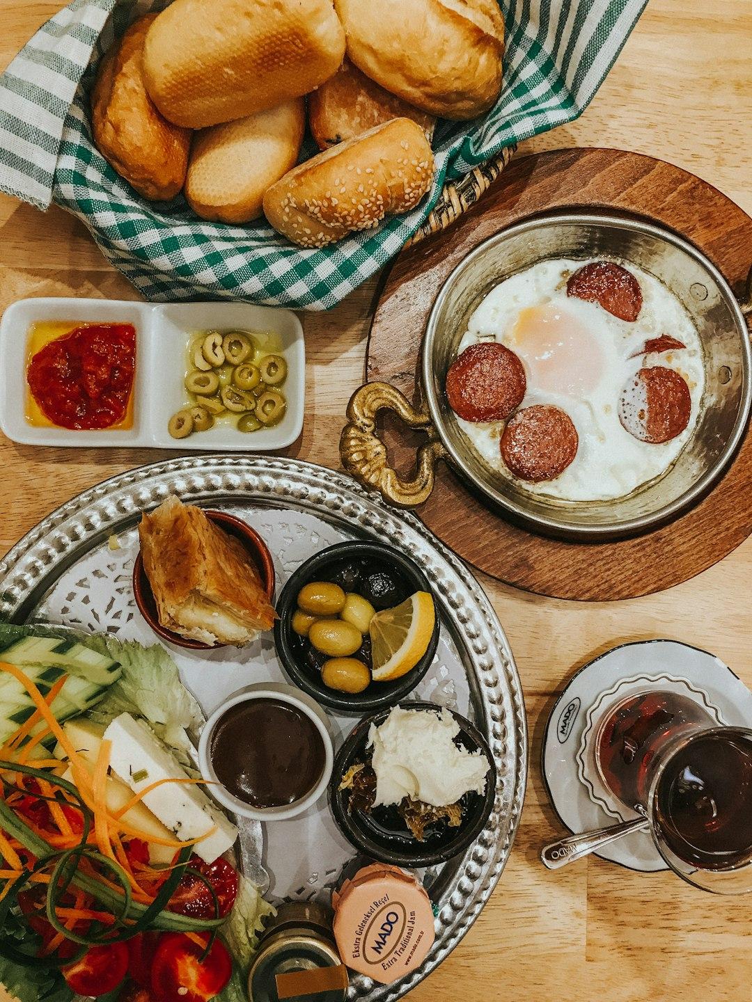 Traditional Turkish breakfast spread with fried eggs and sausage, olives, bread rolls, vegetables, and tea in Istanbul
