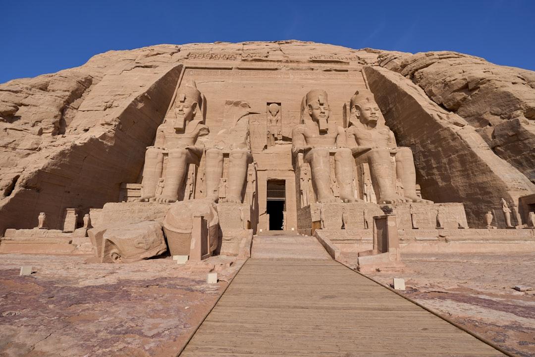 Four colossal seated statues of Ramesses II carved into sandstone cliffs at Abu Simbel Temple, Egypt