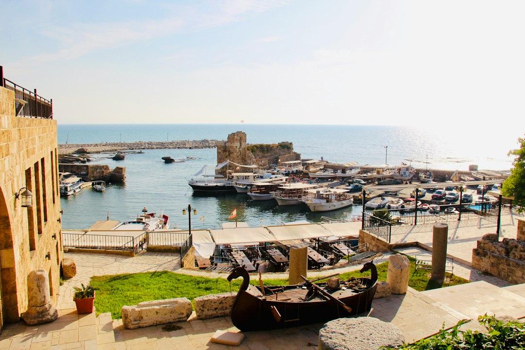 Byblos ancient harbour with moored boats, Crusader tower ruins, and a wooden Phoenician ship replica in the foreground, Lebanon