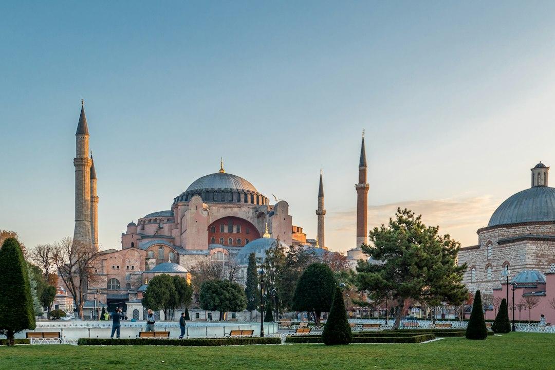 Hagia Sophia's massive dome and minarets glowing at sunset over Sultanahmet Square gardens, Istanbul