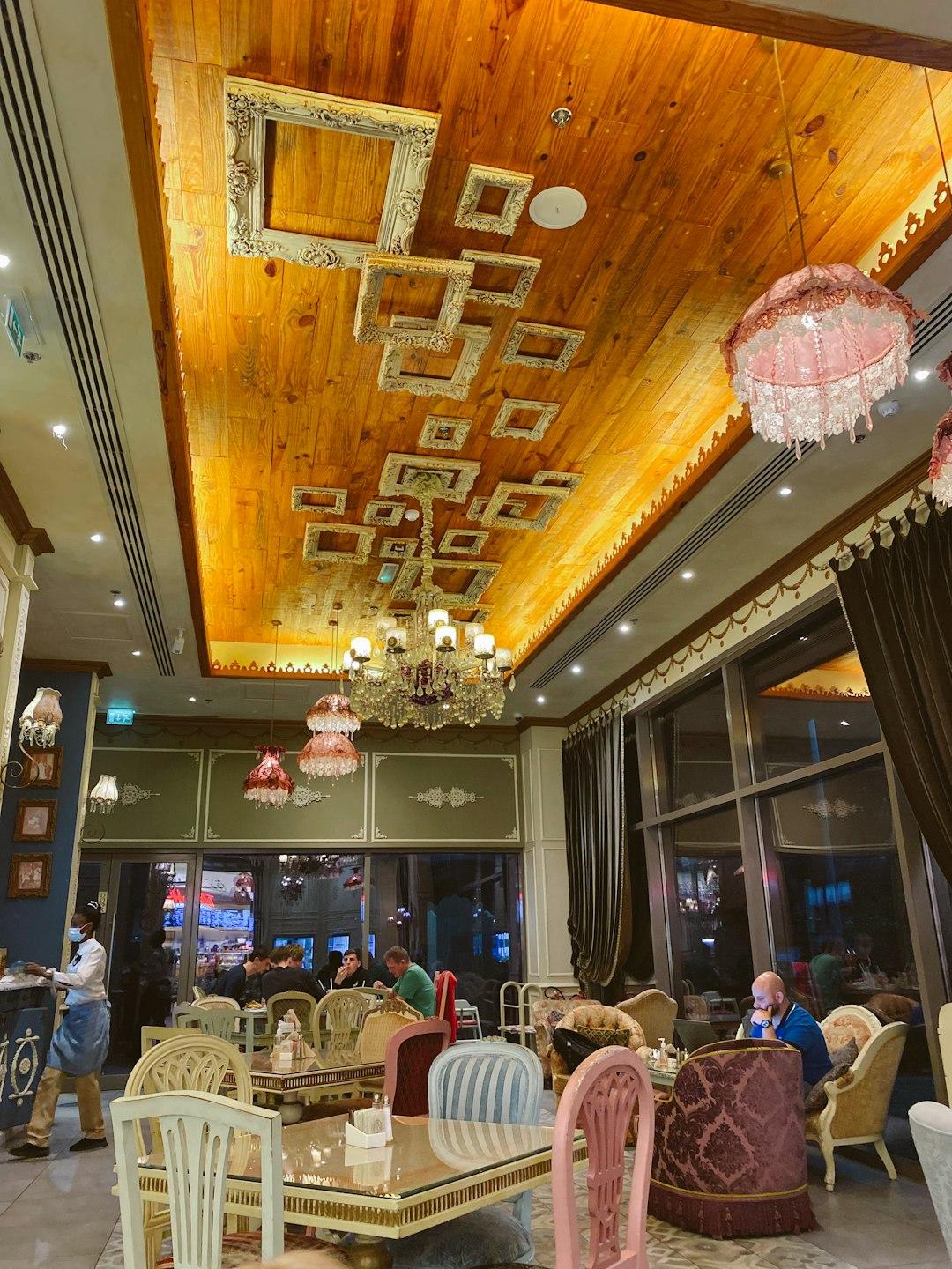 Ornate restaurant interior with wooden ceiling, gilded frames, crystal chandeliers, and mismatched vintage chairs at Al Fanar Dubai
