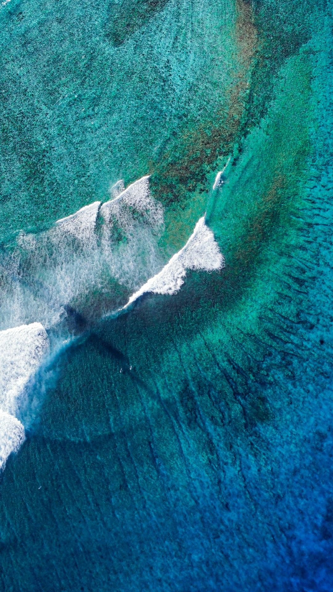 Aerial view of turquoise reef waves breaking over a coral formation in the Maldives