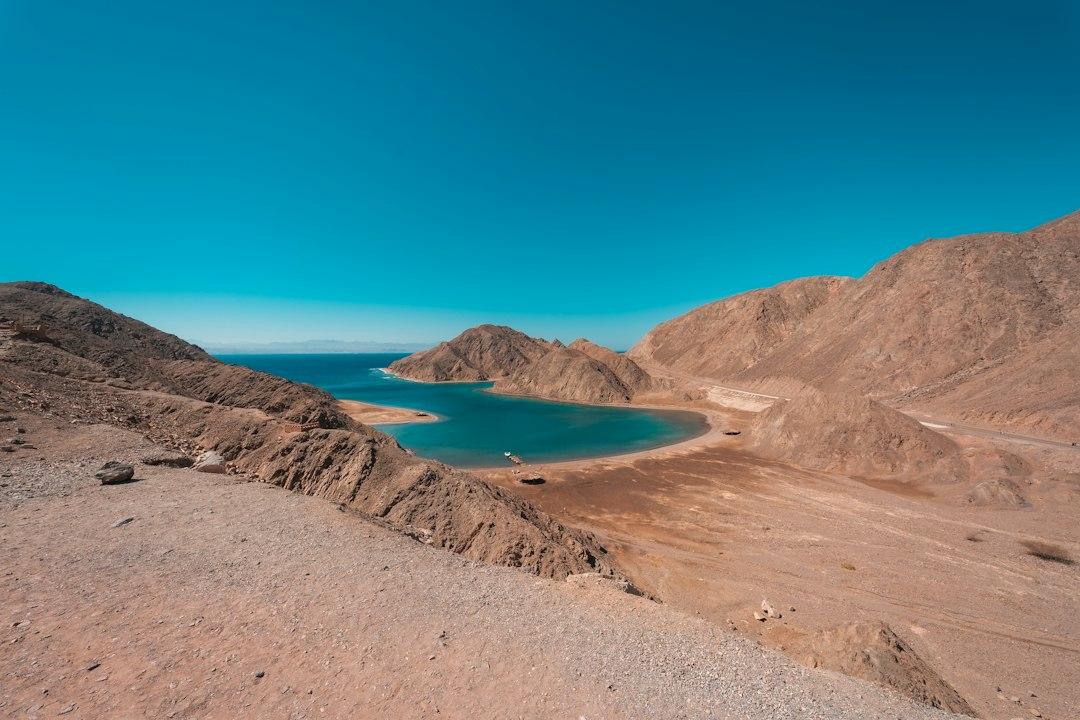Turquoise bay nestled between arid desert mountains in Ras Abu Galum Protectorate, Sinai, under a clear blue sky