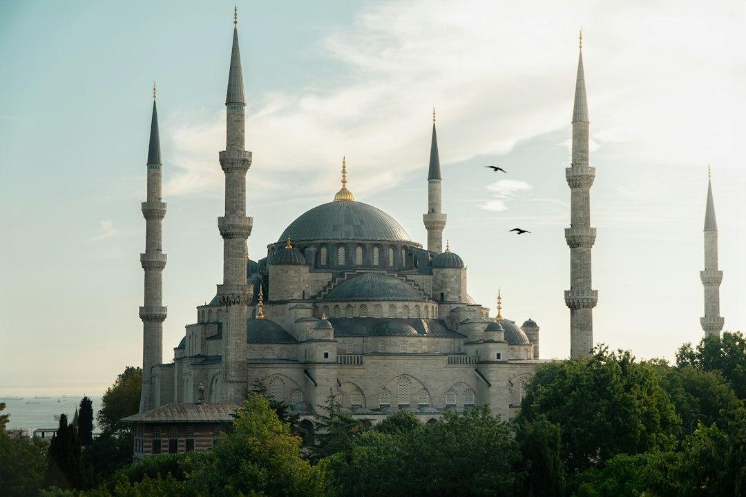 Blue Mosque's cascading domes and twin minarets against a vivid pink-purple sunset sky over the Bosphorus, Istanbul
