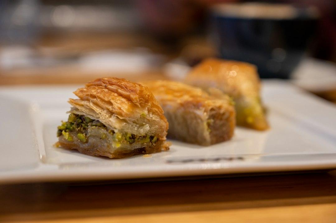 Golden pistachio baklava pieces with flaky phyllo layers on a white plate at Karaköy Güllüoğlu, Istanbul