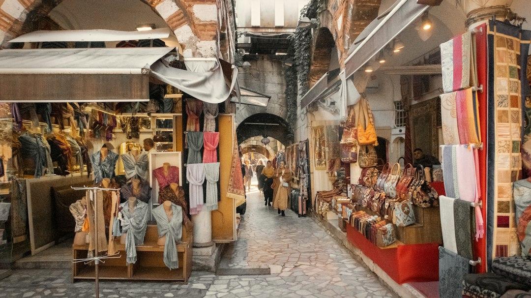 Narrow covered bazaar alley in Istanbul lined with colorful scarves, carpets, and handbags on both sides