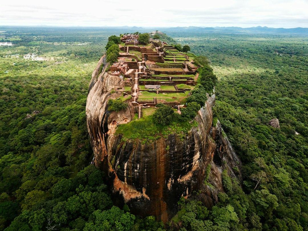 Aerial view of Sigiriya Rock Fortress rising above dense Sri Lankan jungle with ancient ruins on its flat summit